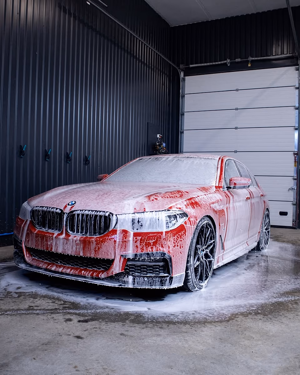 Punainen BMW käsinpesussa vaahdon peitossa